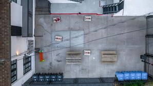 Eine Vogelperspektive eines Innenhofs mit einer Treppe, einem roten Weg und mehreren Holzpaletten.