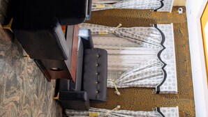 A room with a black sofa, patterned curtains, and a patterned floor.