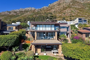 Ein modernes, zweistöckiges Haus mit Balkon, Terrasse und Blick auf die Berge.