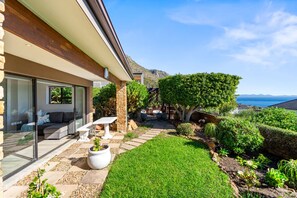 A modern house with a patio, a seating area, and a view of the sea. - Zaria Sun Cottage (Cape Town)