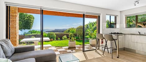 A modern kitchen with a large sliding glass door leading to a garden.