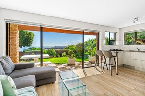 A modern kitchen with a large sliding glass door leading to a garden. - Zaria Sun Cottage (Cape Town)