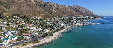 A coastal town with a beach, houses, and mountains.