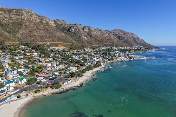 A coastal town with a beach, houses, and mountains.