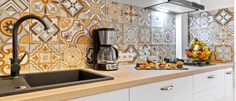 Una cocina con baldosas estampadas, una cafetera y un frutero en la encimera.