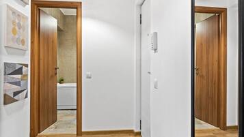 Ein Korridor mit Holztüren, einer weißen Wand und einem gefliesten Boden.