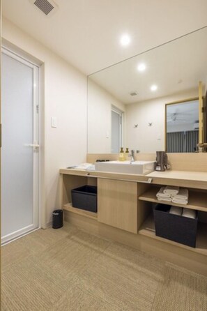 A modern bathroom with a large mirror, a sink, and storage cabinets. - ALPHABED INN NahaKokusaiStreet WEST (Naha)