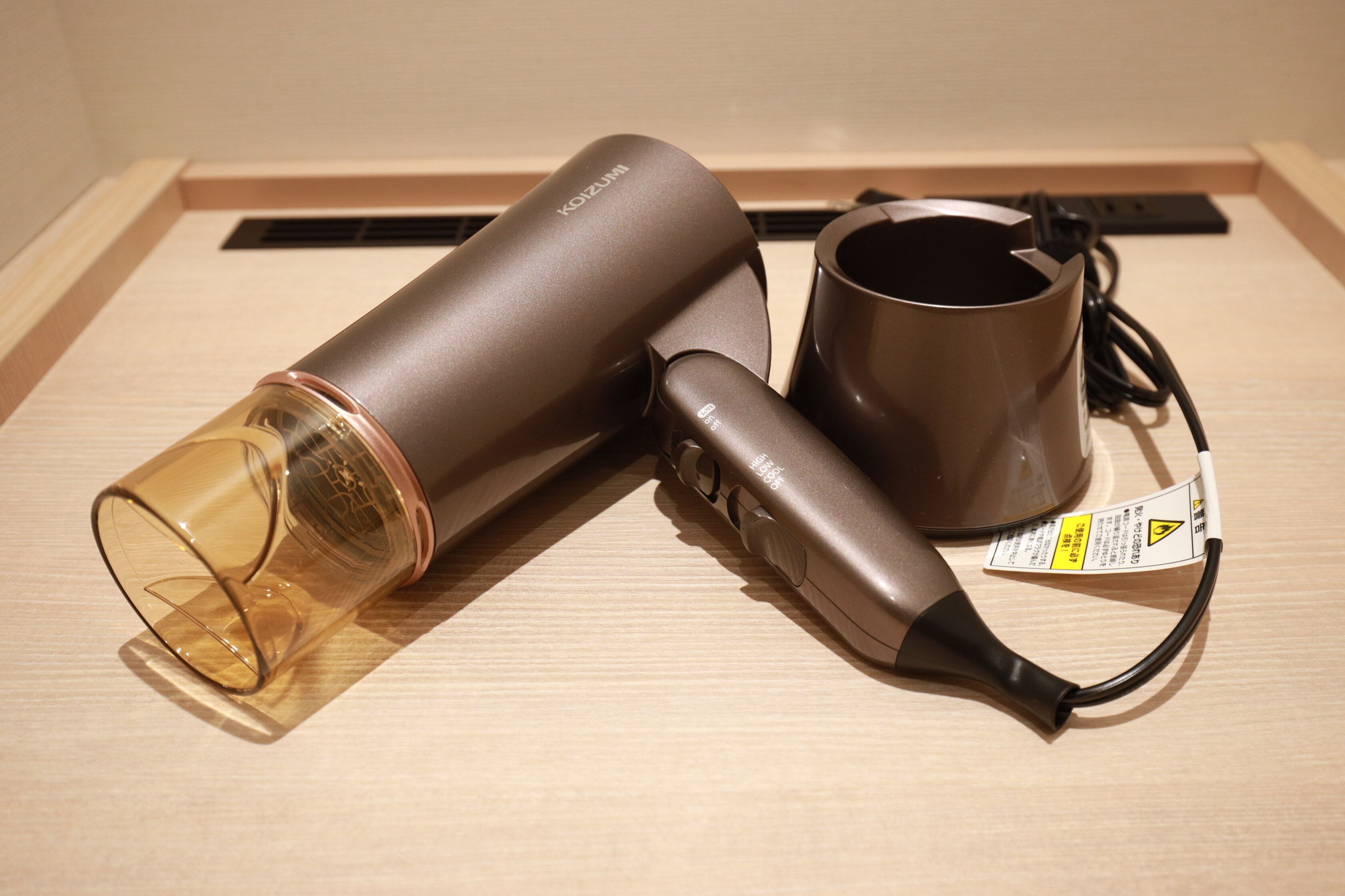 Un secador de pelo y una taza sobre una superficie de madera.