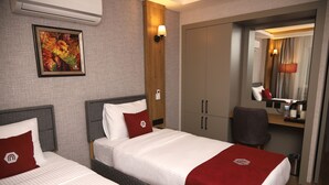 A hotel room with two beds, a desk, a chair, a wardrobe, and a mirror. - Rush Otel Tokat (Tokat)