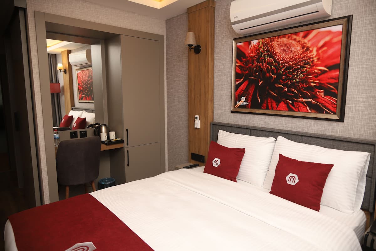 A hotel room with a bed, a desk, a chair, and a large window.