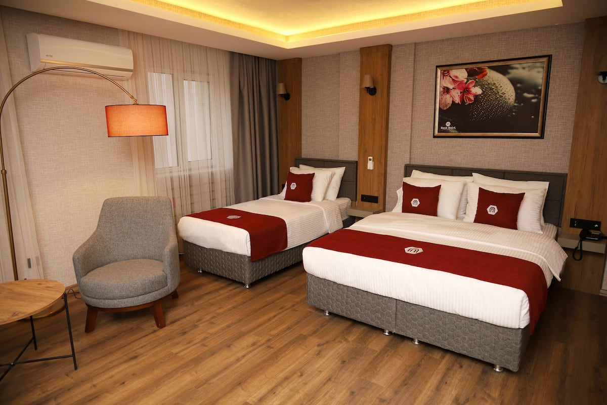 A hotel room with two beds, a chair, a lamp, and a painting on the wall.