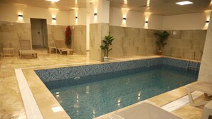 An indoor swimming pool with clear water, surrounded by lounge chairs and a tiled floor. - Rush Otel Tokat (Tokat)