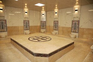 A large, well-lit bathroom with a central circular design on the floor, surrounded by four toilets and decorative wall panels.