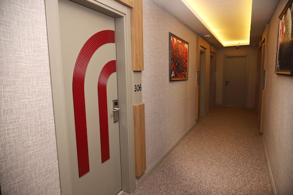 A hallway with a door marked '306', a red accent on the door, and a framed picture on the wall.