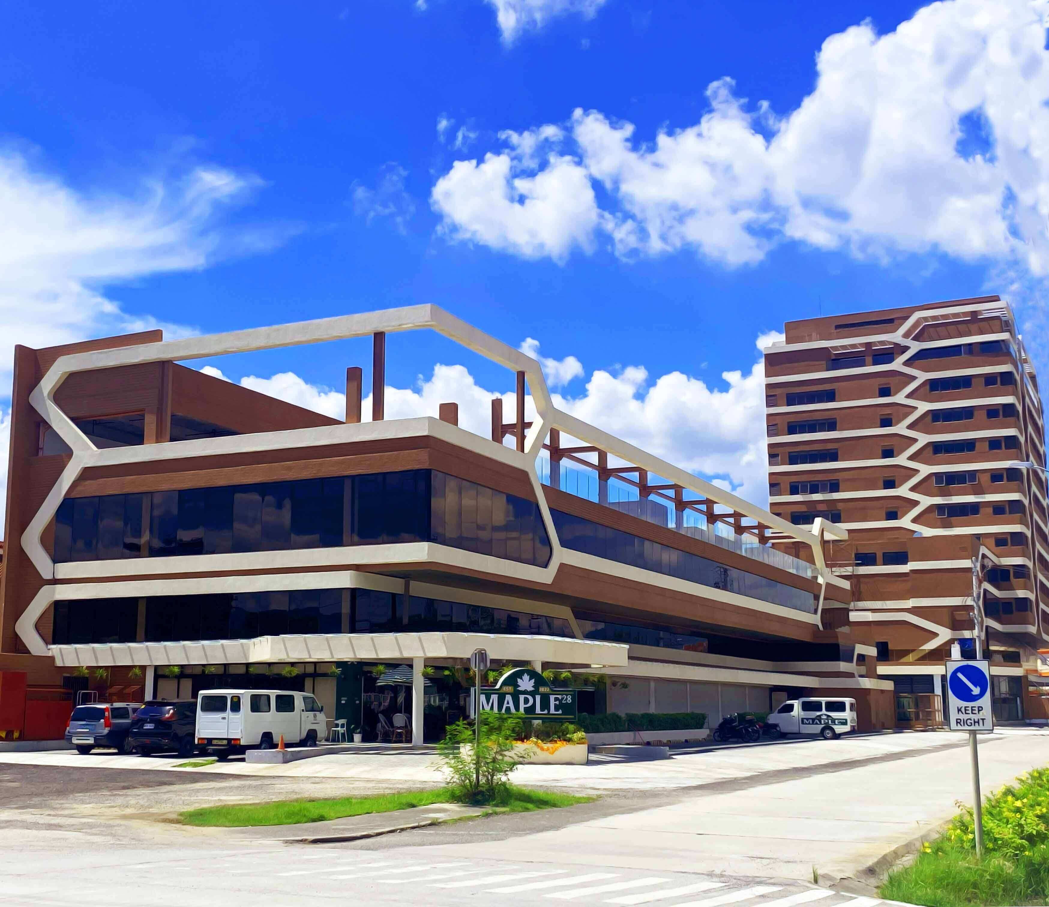 A modern multi-story building with a unique angular design, featuring a prominent 'Maple' sign at the entrance.