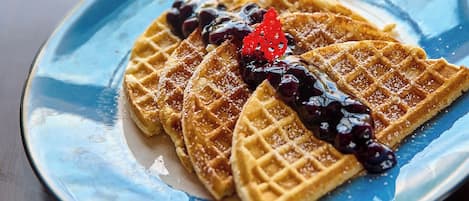 Une assiette de gaufres servies avec du sirop et une compote de fruits rouges.