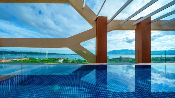 A modern infinity pool with a clear view of a mountainous landscape and a body of water. - The Aurora Subic Hotel Managed by HII (Olongapo)