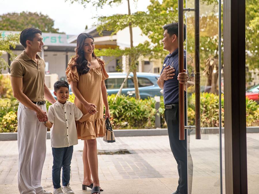 A family of four standing at a glass door entrance of a building.