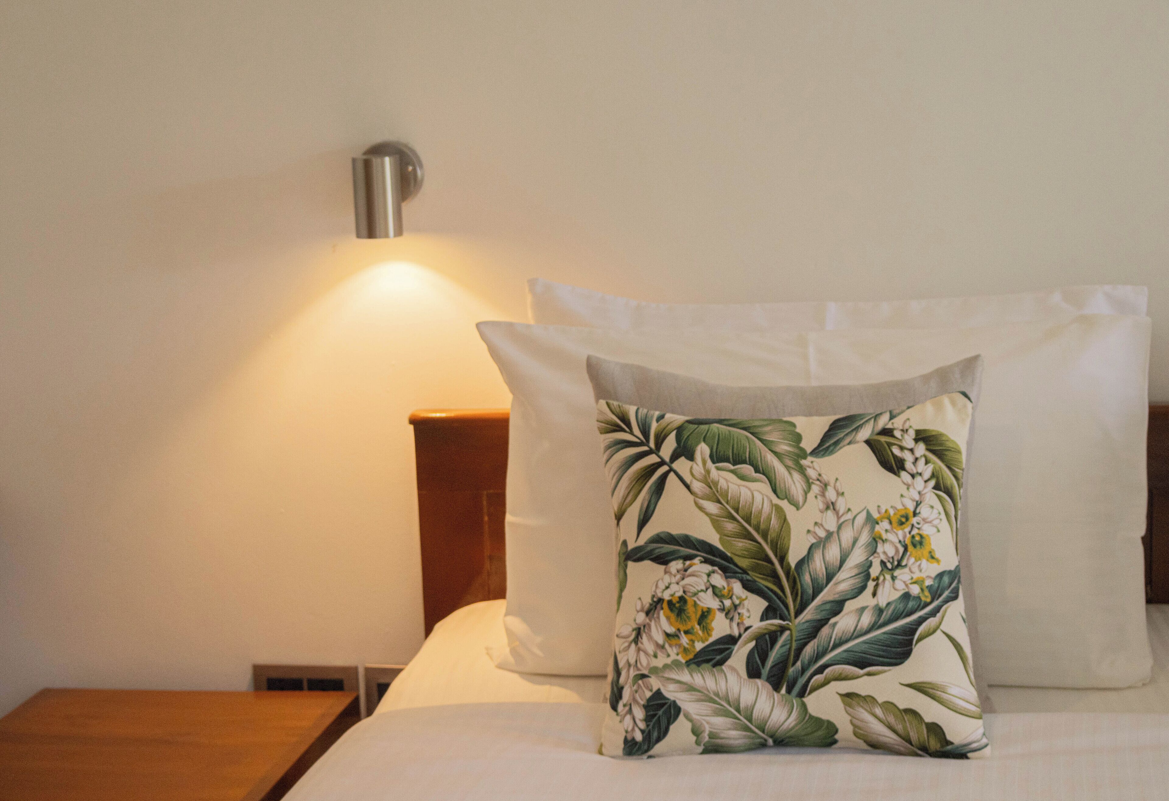 Un letto rifatto con cuscini floreali e una lampada da comodino.