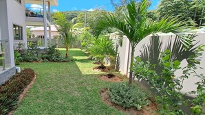A modern building with a well-maintained garden, including various plants and a lawn. - Palm Holiday Apartments (Praslin Island)