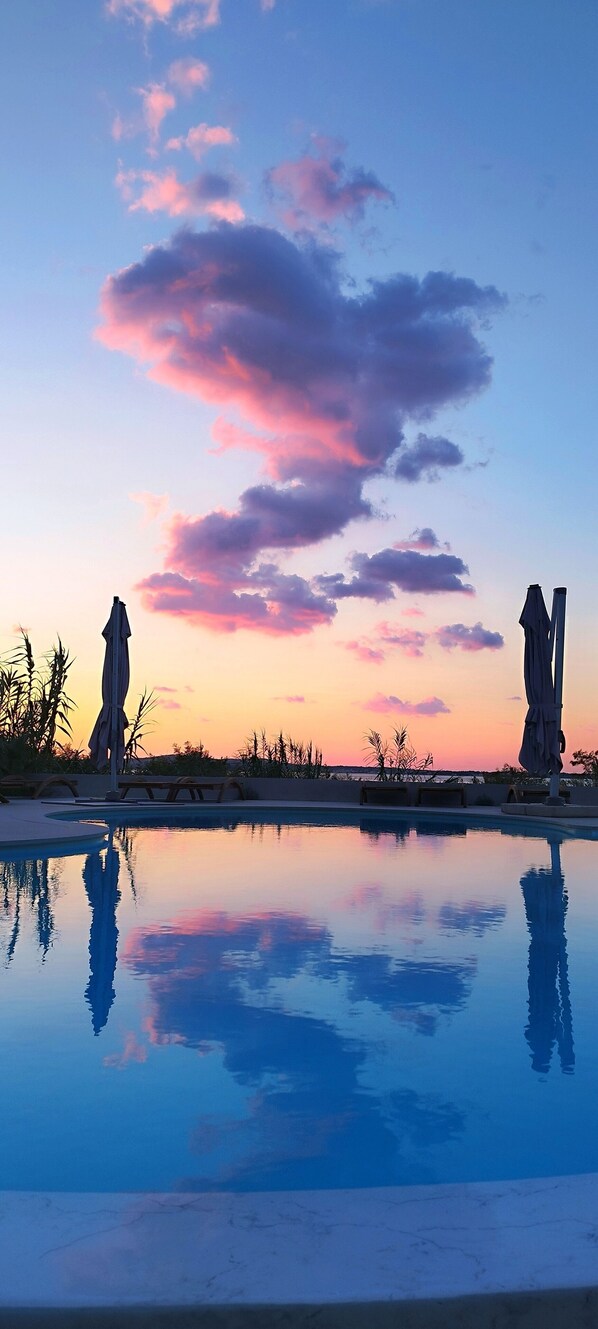 Relax by the serene pool surrounded by statues and lush greenery.