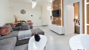 Een moderne woonkamer met een bank, salontafel en een aan de muur bevestigde televisie.