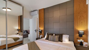 Een hotelkamer met een groot bed, een spiegel, een houten hoofdbord en een nachtkastje met een lamp.