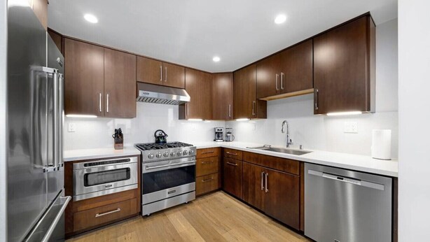 A modern kitchen with stainless steel appliances, wooden cabinets, and a white countertop. - La Jolla Ocean Front Escape (San Diego)