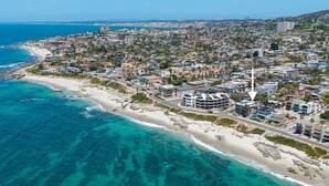 An aerial view of a coastal city with a beachfront, dense residential area, and a prominent building with a pointed roof. - La Jolla Ocean Front Escape (San Diego)