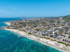 An aerial view of a coastal city with a beachfront, dense residential area, and a prominent building with a pointed roof. - La Jolla Ocean Front Escape (San Diego)