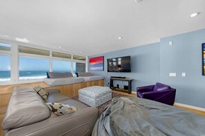 A modern living room with a large window, a flat-screen TV, and a comfortable seating area. - La Jolla Ocean Front Escape (San Diego)