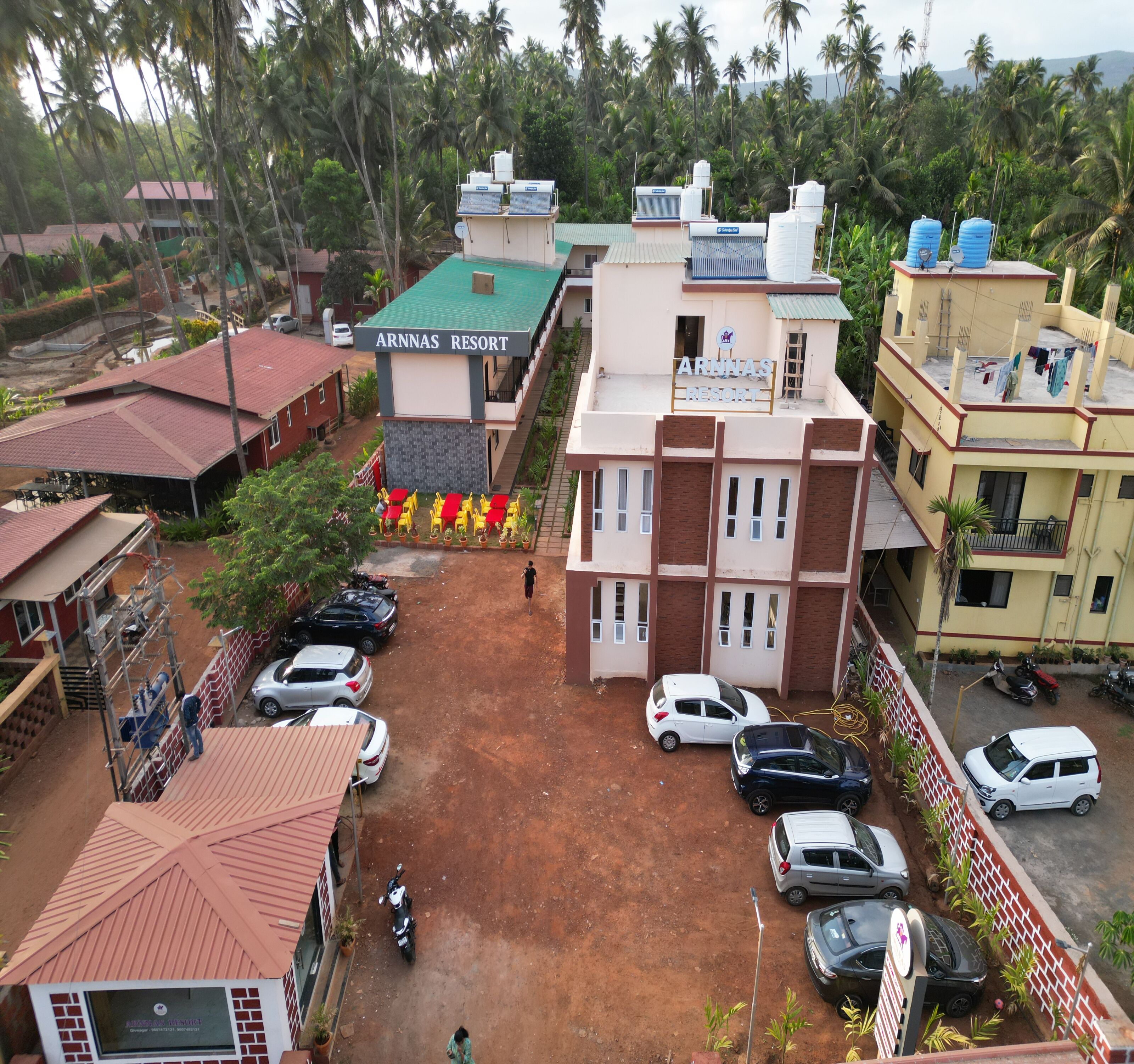 A resort with multiple buildings, a parking area, and a surrounding landscape with palm trees.