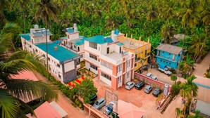 A resort with multiple buildings, a parking area, and a lush green landscape with palm trees. - Arnnas Resort Diveagar (Shrivardhan)