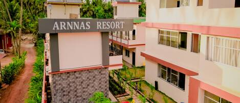 A resort with multiple buildings, a sign reading "ARNNAS RESORT", and a pathway surrounded by greenery.