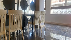 A room with a tiled floor, white chairs, and a large window with a view of the outside. - Amman Trail Hotel & Studios (Amman)