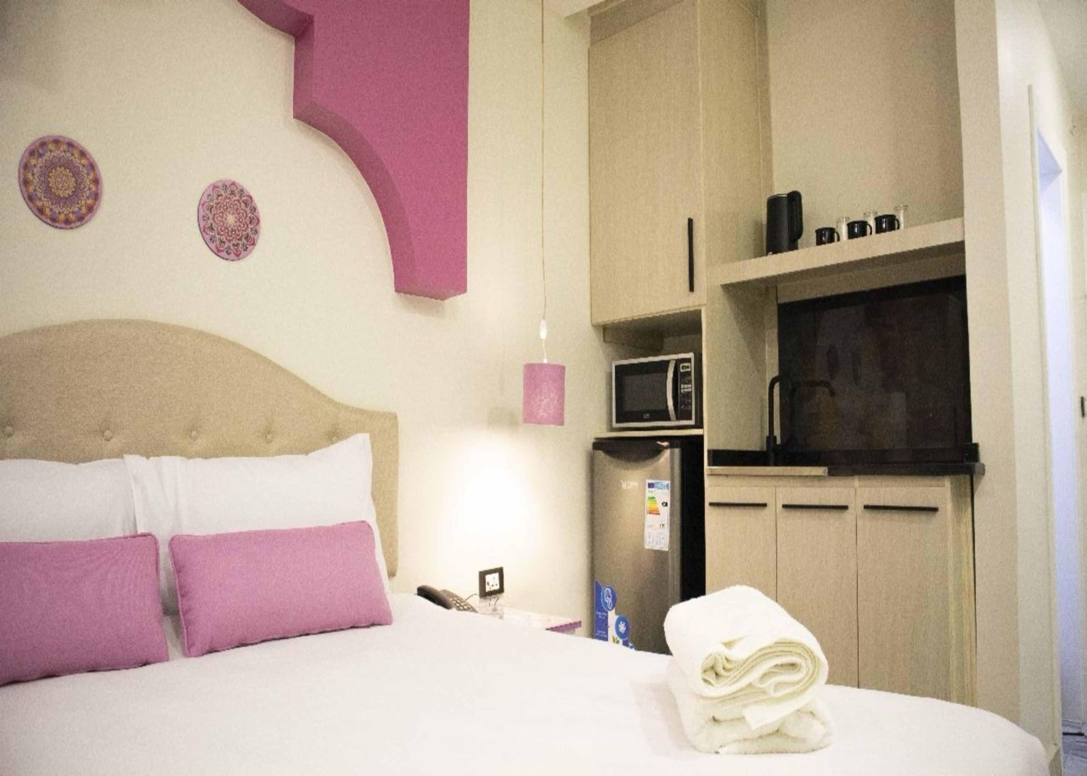 A hotel room with a bed, a microwave, a refrigerator, and a small kitchenette.