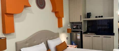 Habitación de hotel con una cama, microondas, refrigerador y televisor.