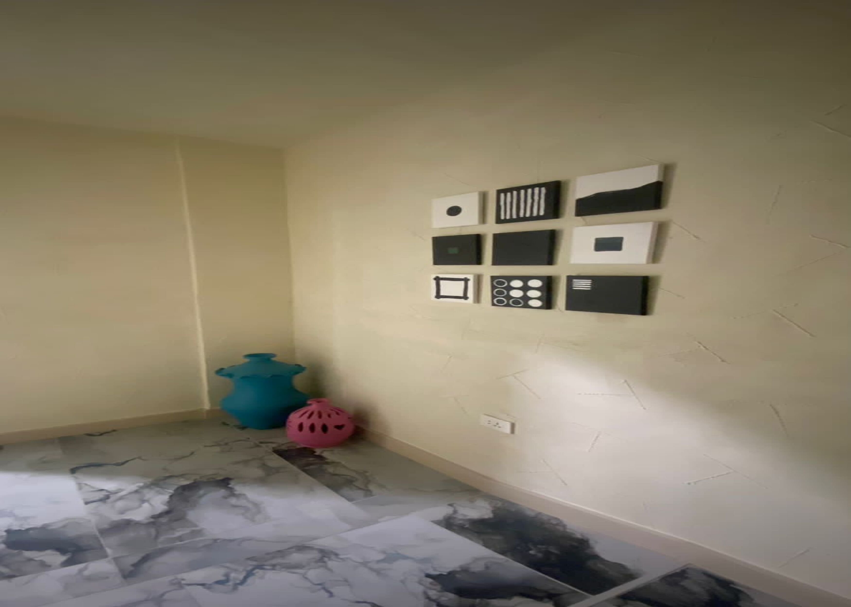 A room with a marble floor, a blue vase, and a pink helmet on the floor.