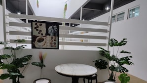 A modern indoor seating area with a marble table and four stools, surrounded by large potted plants.