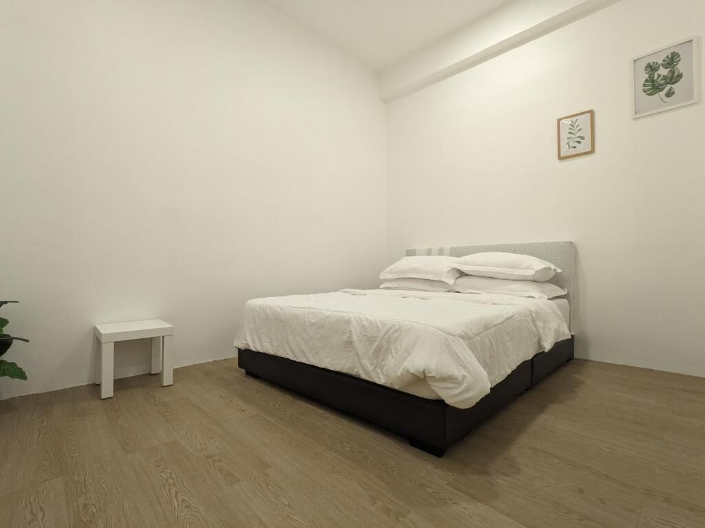 A bedroom with a bed, a small bedside table, and a potted plant.