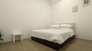 A bedroom with a bed, a small bedside table, and a potted plant.