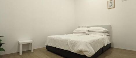 A bedroom with a bed, a small bedside table, and a potted plant.