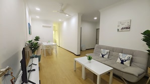 A modern living room with a sofa, a coffee table, and a dining area with a table and chairs.