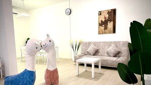 A living room with a sofa, coffee table, and two large stuffed animals.