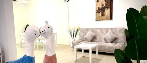 A living room with a sofa, coffee table, and two large stuffed animals.