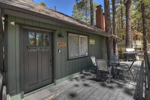 A wooden deck with outdoor furniture, a door with a number sign, and a building with a green exterior.