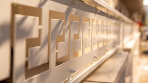 Een close-up van een witte metalen leuning met geometrische uitsnijdsels.