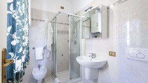 Ein modernes Badezimmer mit einer Duschkabine, einem weißen Waschtisch und einem Bidet.