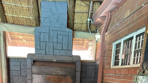 Uma cozinha de pedra com forno embutido, pia e janela com grades.