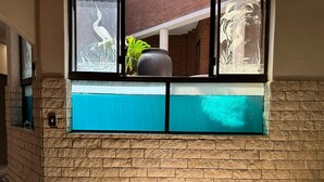 A window with a view of a bird, a plant, and a decorative panel. - Koi Liv-Inn (Germiston)